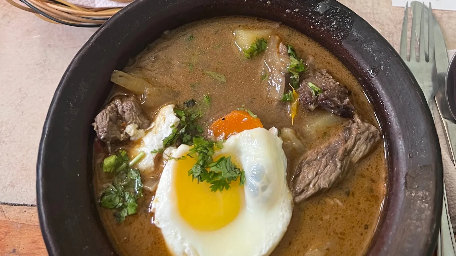 Ajiaco con carne, papas y huevo, servido en greda